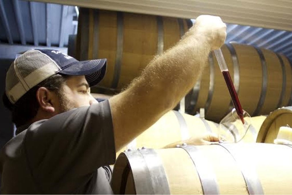 man filling a wine glass from a barrel at Beans Creek Winery; photo courtesy of beans creek winery