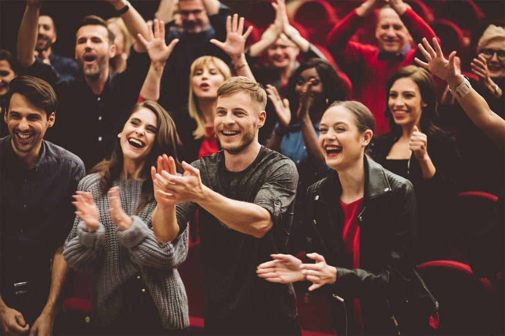 crowd laughing and clapping at a comedy show