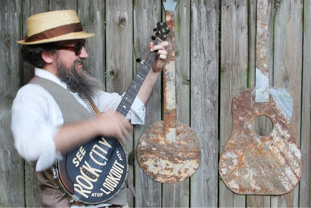 A baseball field at sunset, with a scoreboard displaying the game details and mountains in the background.
