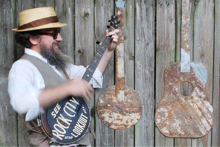 A baseball field at sunset, with a scoreboard displaying the game details and mountains in the background.