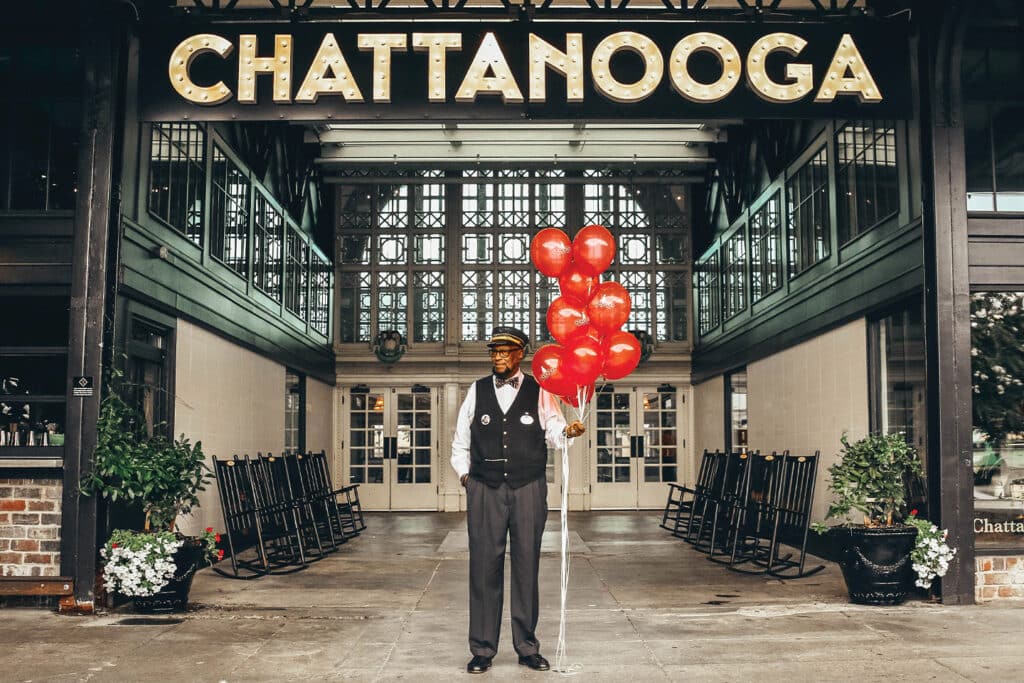 Chattanooga Choo Choo conductor holding balloons under Chattanooga marquee.