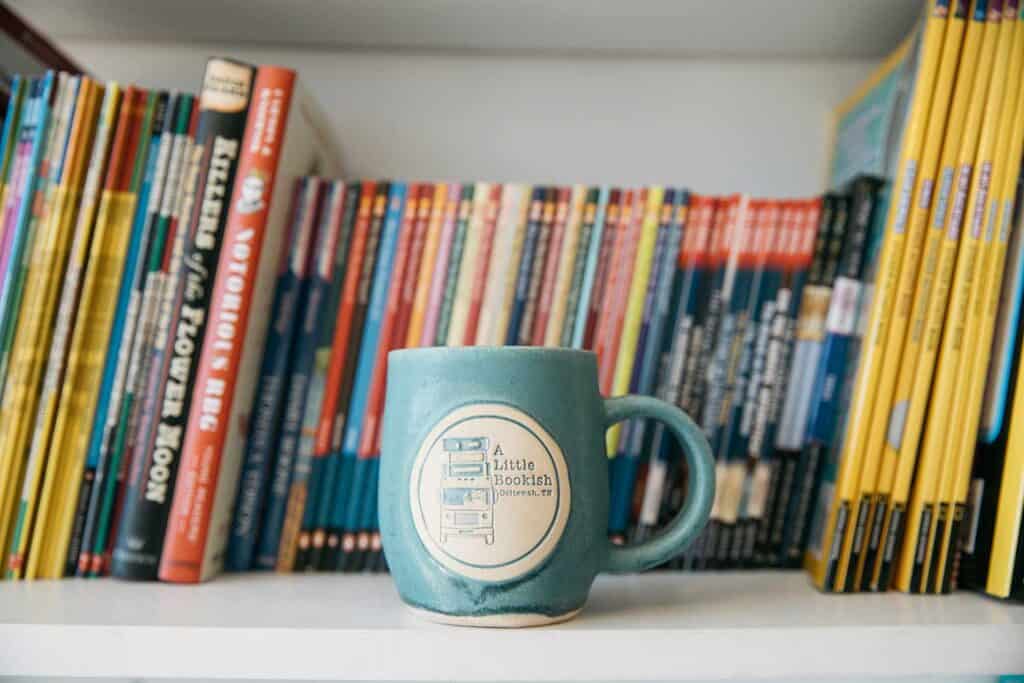 A Little Bookish store shelf with books and branded mug