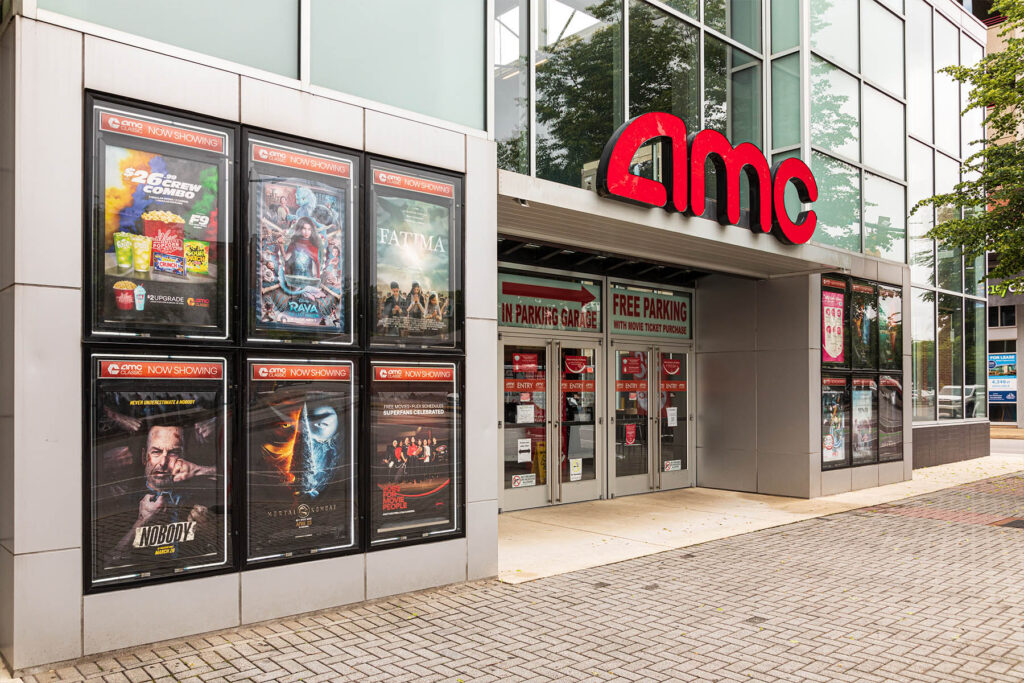 Modern AMC theater entrance with large glass windows and a prominent red AMC logo