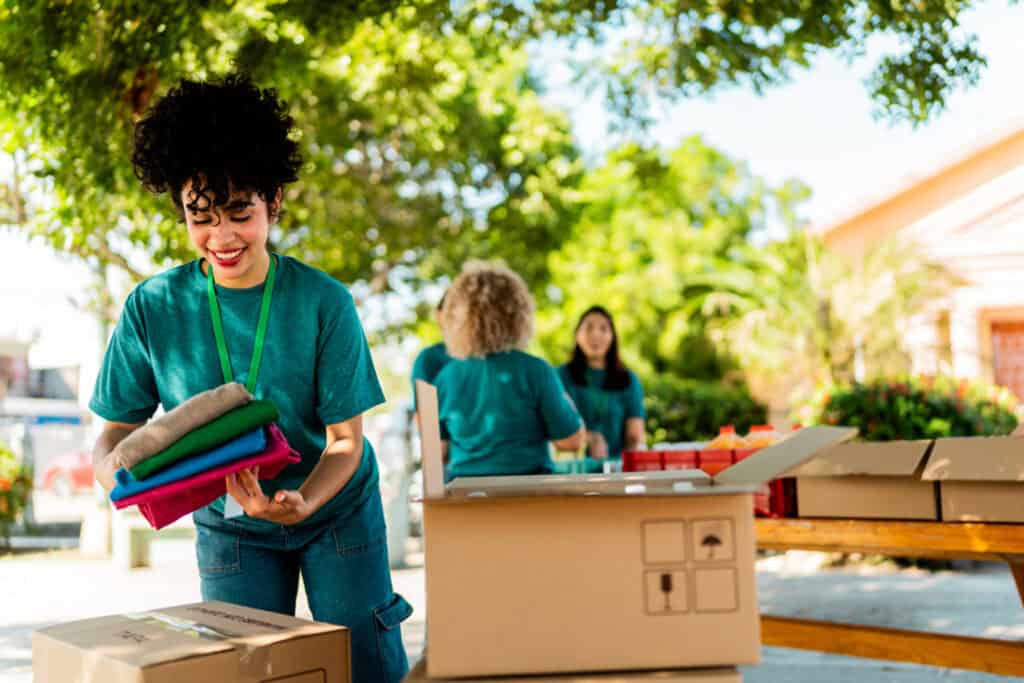 Two men in light blue shirts examine artifacts on a table, discussing enthusiastically in an outdoor setting.