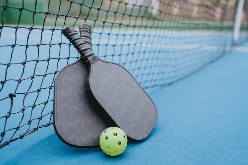 pickleball rackets laying on a pickelball net
