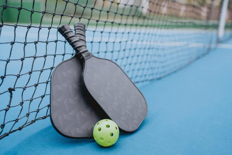 pickleball rackets laying on a pickelball net