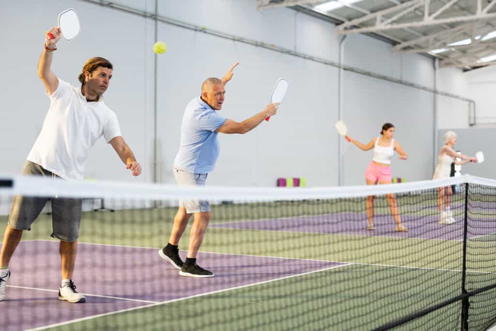 people playing pickelball in an indoor court