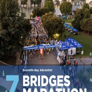 Aerial view of a marathon event with participants, tents, and a scenic waterfront backdrop.