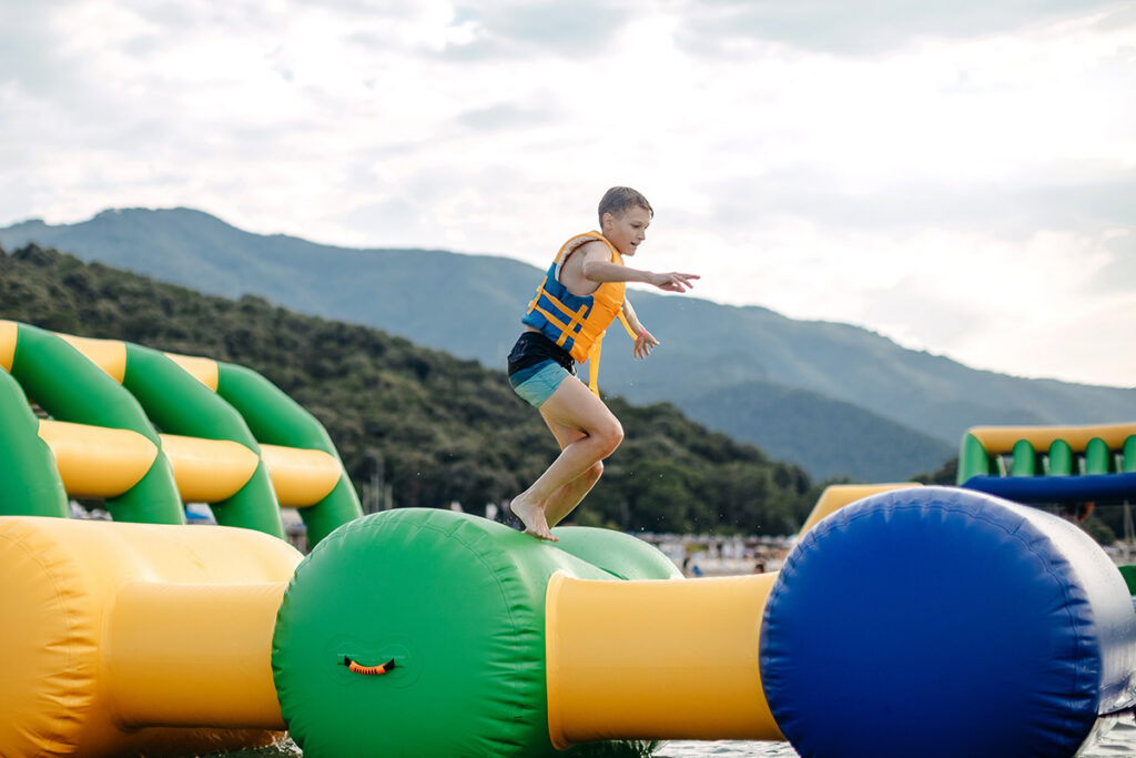 boy running across floating water obstacle course